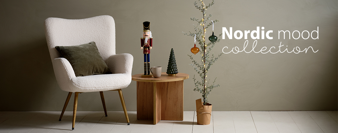 Poltrona con cuscino, tavolino con statuetta schiaccianoci e un sottile albero di Natale decorato con palle di vetro