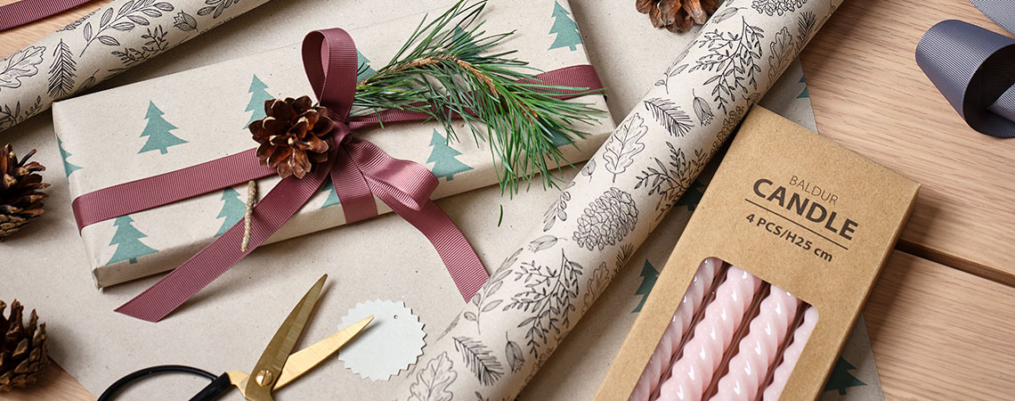 Un tavolo con carta da regalo, decorazioni natalizie e regali  