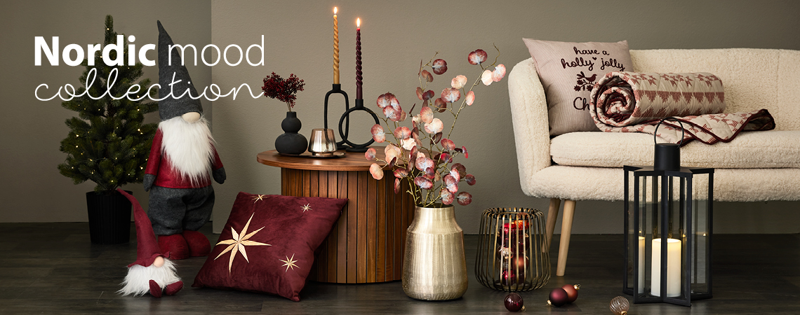 Elfi di Natale, cuscini, vaso dorato con fiore artificiale, candeliere dorato e lanterna nera davanti a un divano bianco