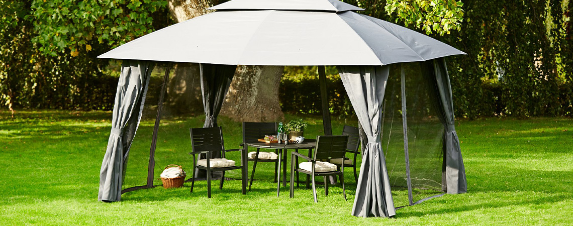 Gazebo grigio con tavolo e sedie da pranzo sul prato del giardino