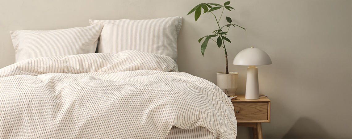 Letto con biancheria a righe in una camera da letto con comodino e lampada