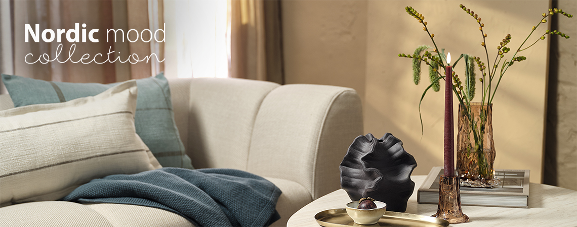 Soggiorno con divano, tavolino da caffè con vaso di vetro e portacandele.