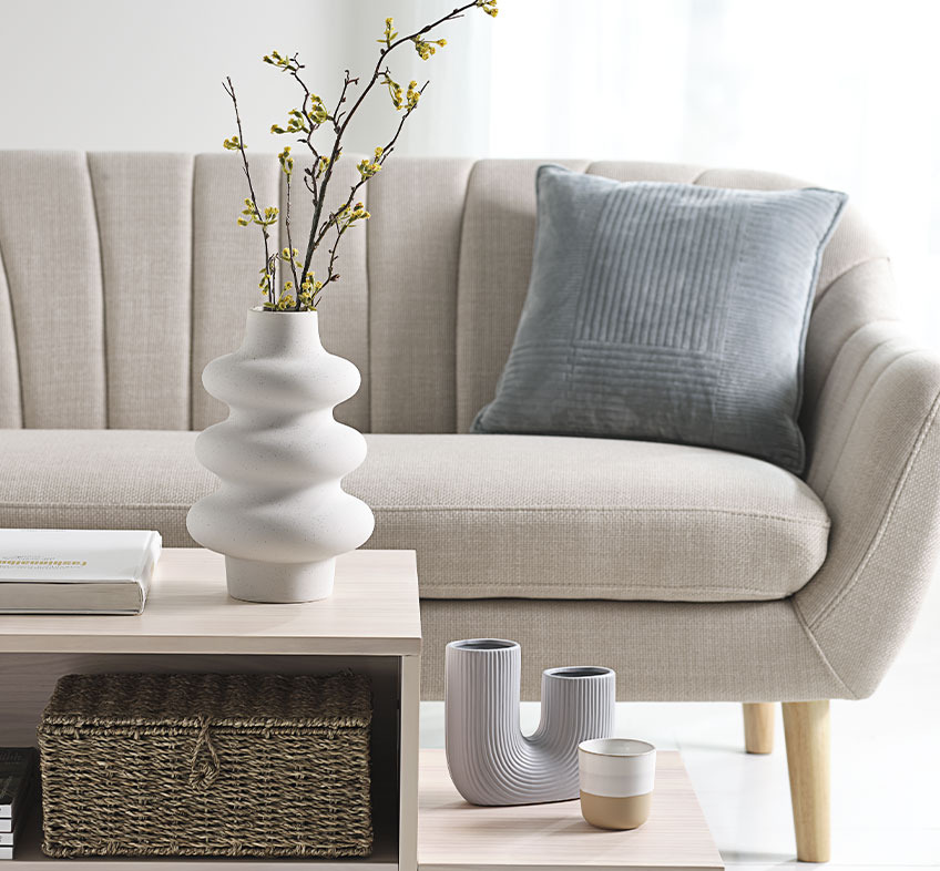 Vaso bianco ALVIS, vaso TORMUND e tazza FREDERIK Soggiorno luminoso con vasi di design sul tavolino e divano beige