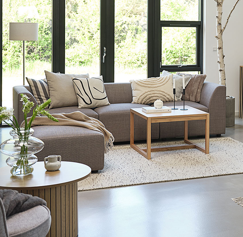 Tavolino da caffè in quercia minimalista in luminoso soggiorno con ampio divano e cuscini decorativi
