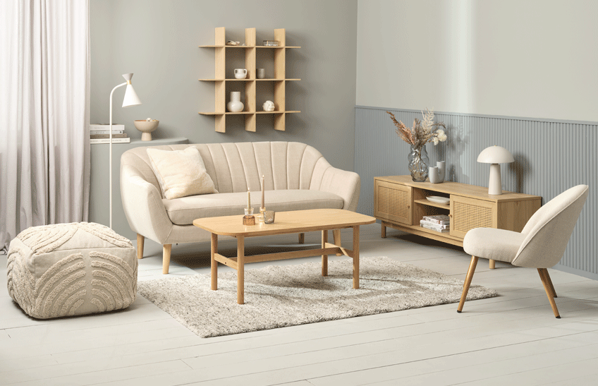 Divano a 2,5 posti color beige, con poltroncina e pouf beige, tavolino in legno chiaro e tappeto beige