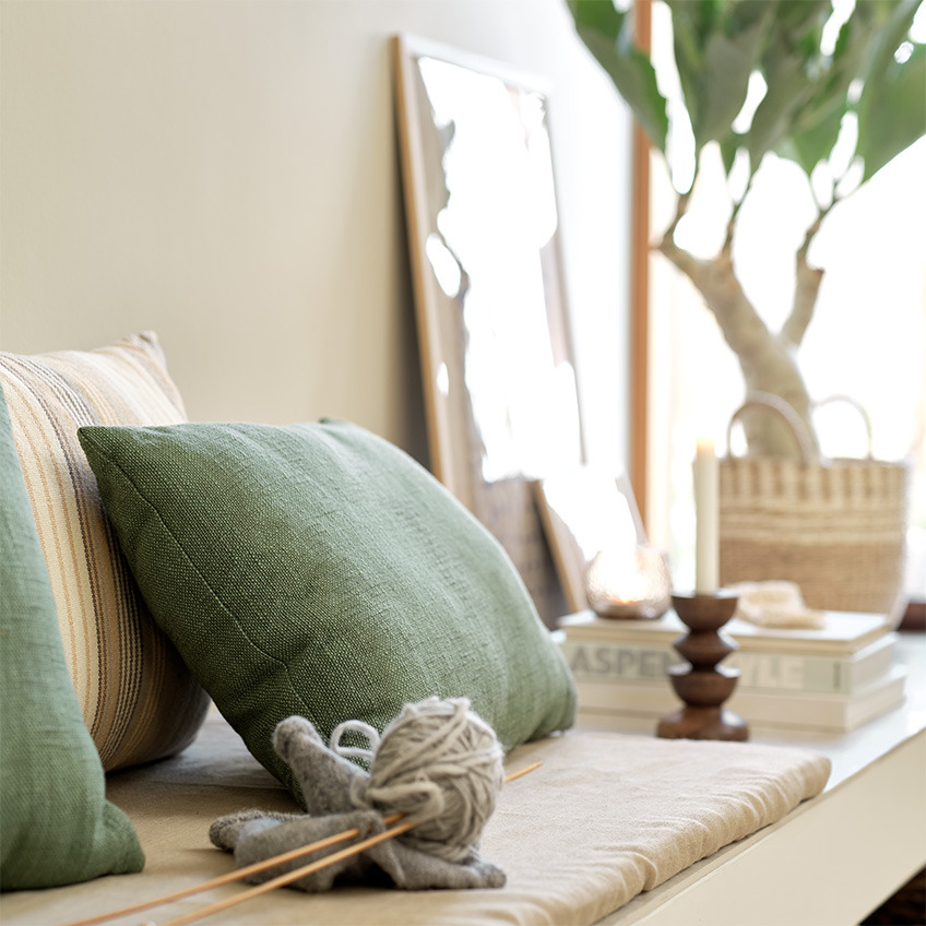 Cuscini verde e a righe insieme ad altre decorazioni per decorare un angolo relax