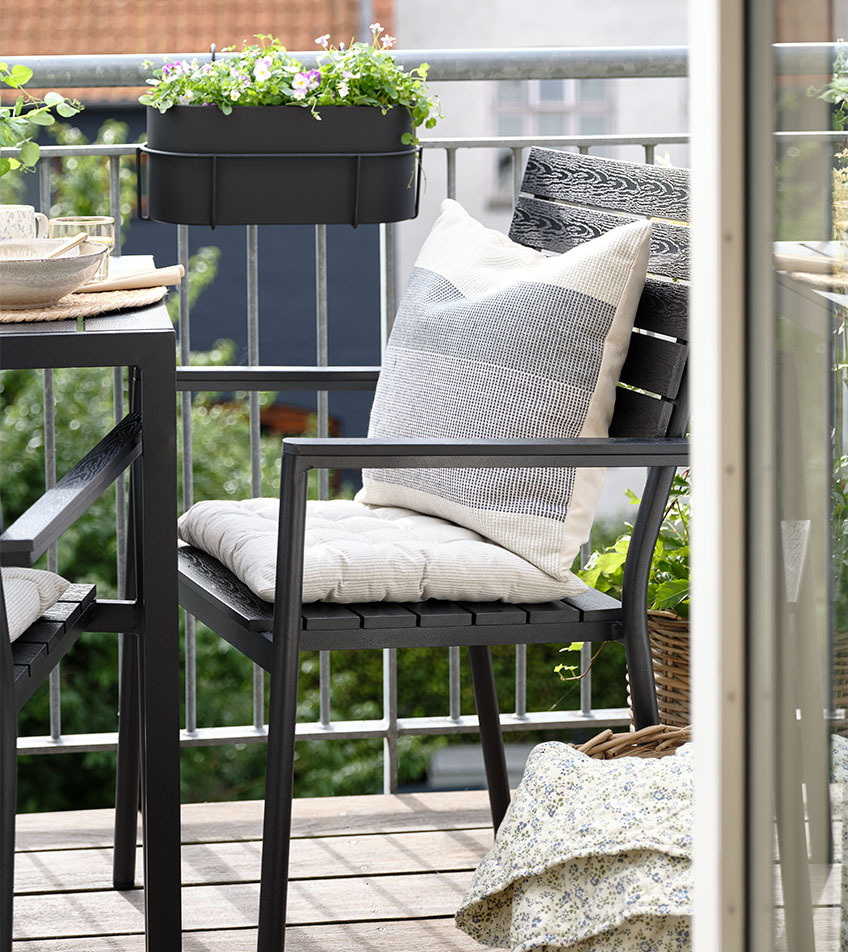Sedia da giardino impilabile nera con cuscini su un balcone