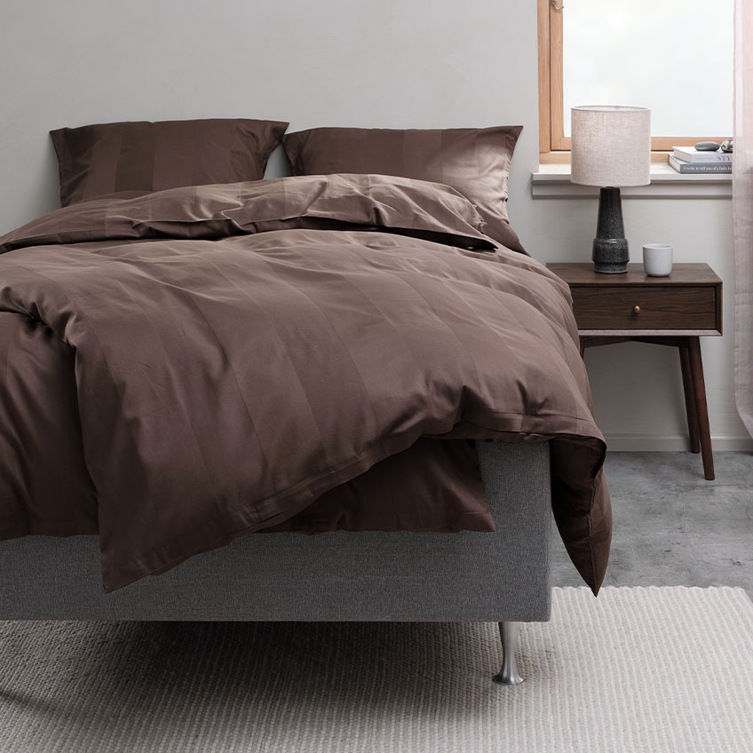Set copripiumino marrone cioccolato e biancheria da letto in cotone sul letto in camera da letto