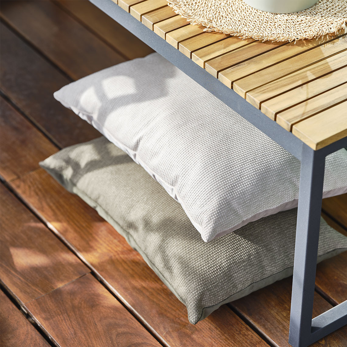 Cuscini beige sistemati sotto una panca da giardino, pronti a offrire comfort extra durante i momenti di relax all’aperto