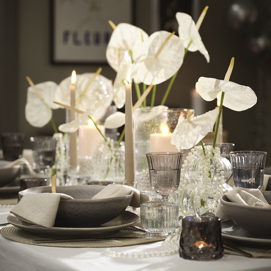 Tavola apparecchiata con tante portacandeline e candele accese, vasi di fiori e altri dettagli festosi