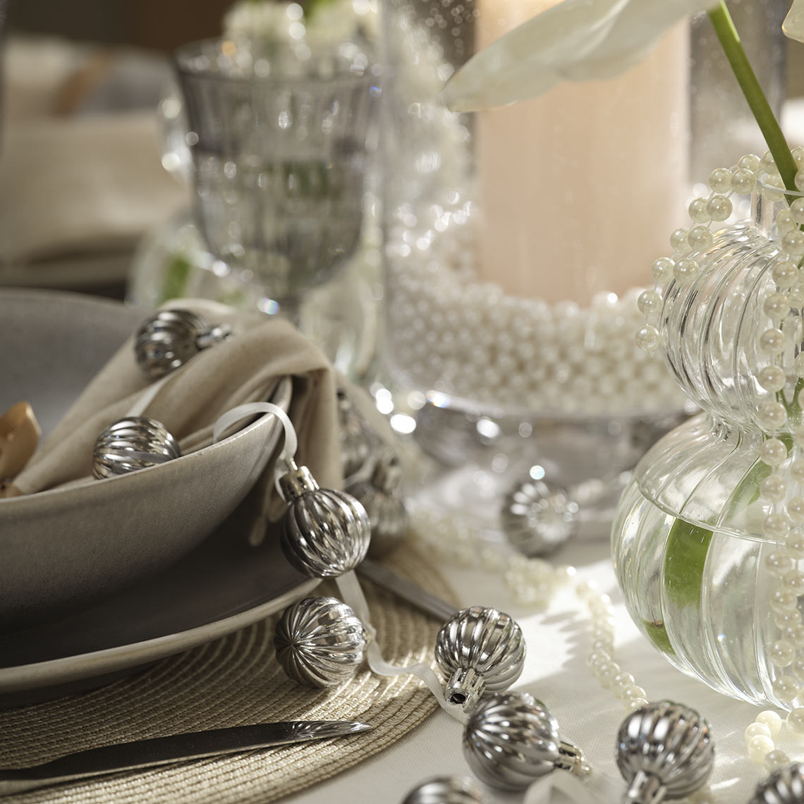 Dettaglio di catena di palline argentate di Natale su tavola imbandita