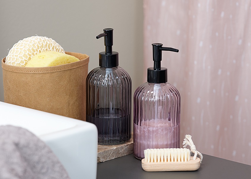 Glass soap dispensers in different colours, sponges and a nail brush 