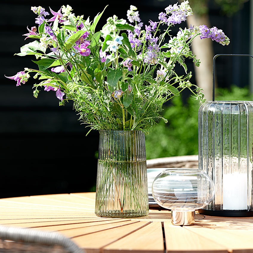 Vaso in vetro e lanterna su tavolo da giardino in teak 