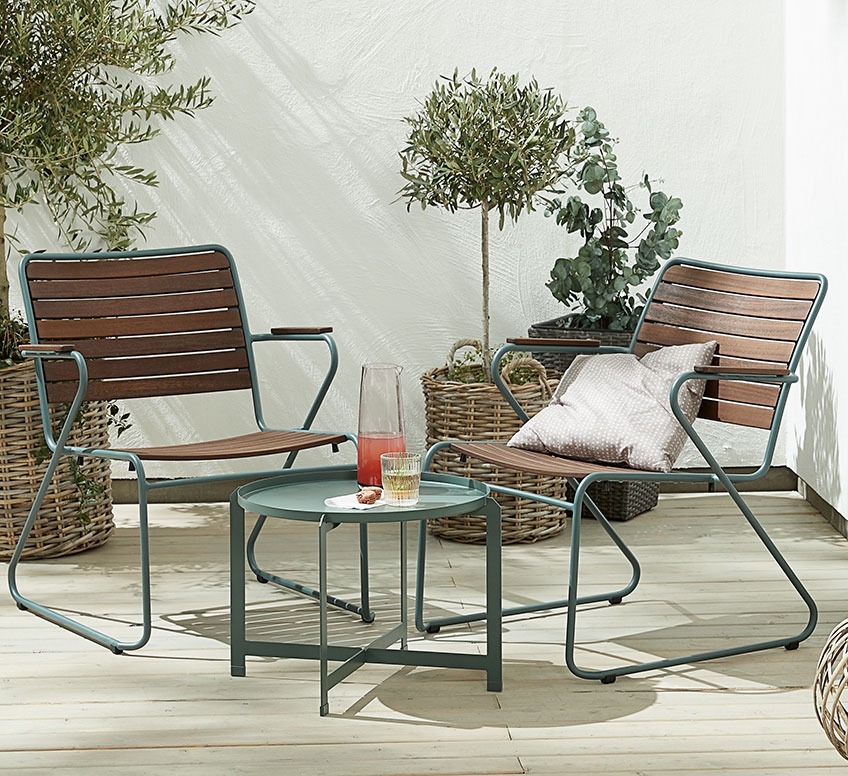 Two wooden garden lounge chairs with green frame and a small green side table on a patio
