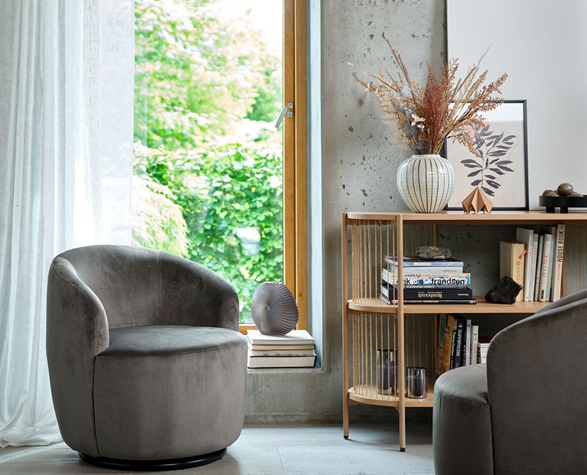 Poltrona e credenza grigia con libri e vaso