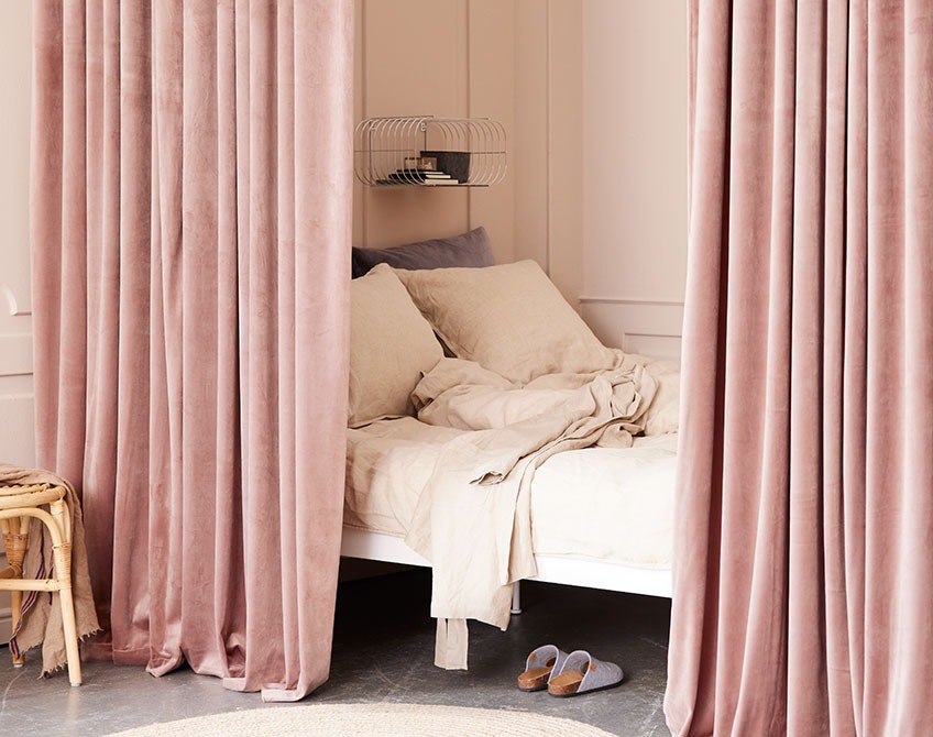 Tende di colore rosa usate per separare una zona notte da un grande soggiorno 	