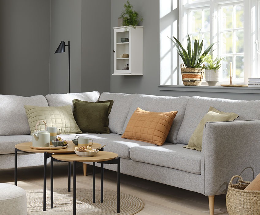 Ambientazione del soggiorno con divano grigio e cuscini arancioni, verdi e beige