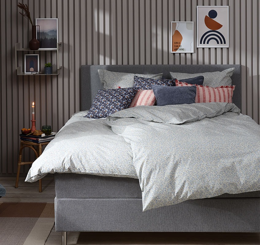 Camera da letto in stile shabby chic con biancheria da letto in stile floreale azzurro chiaro e cuscini decorativi
