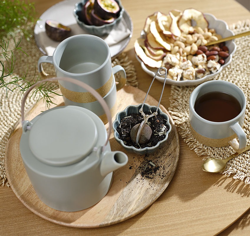 Vassoio di legno con teiera verde e tazze e ciotoline con snack e tè