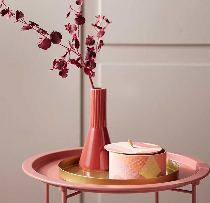 Vaso rosso e scatola rotonda su un vassoio decorativo color ottone