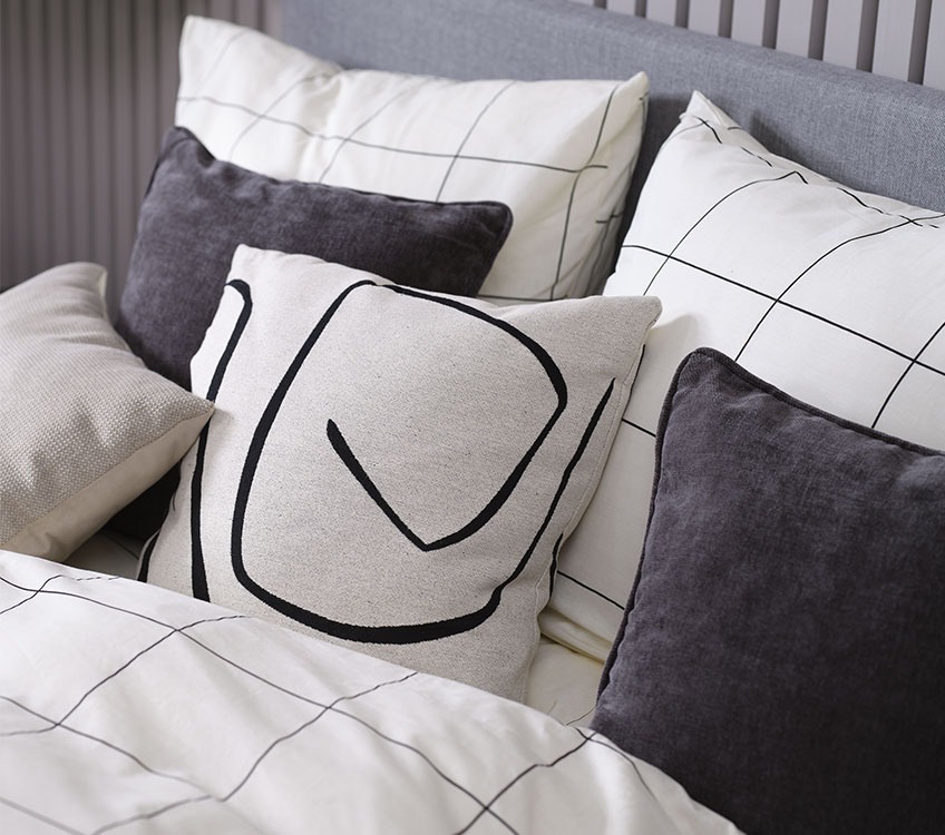 Camera da letto con biancheria da letto bianca e nera con cuscini decorativi  