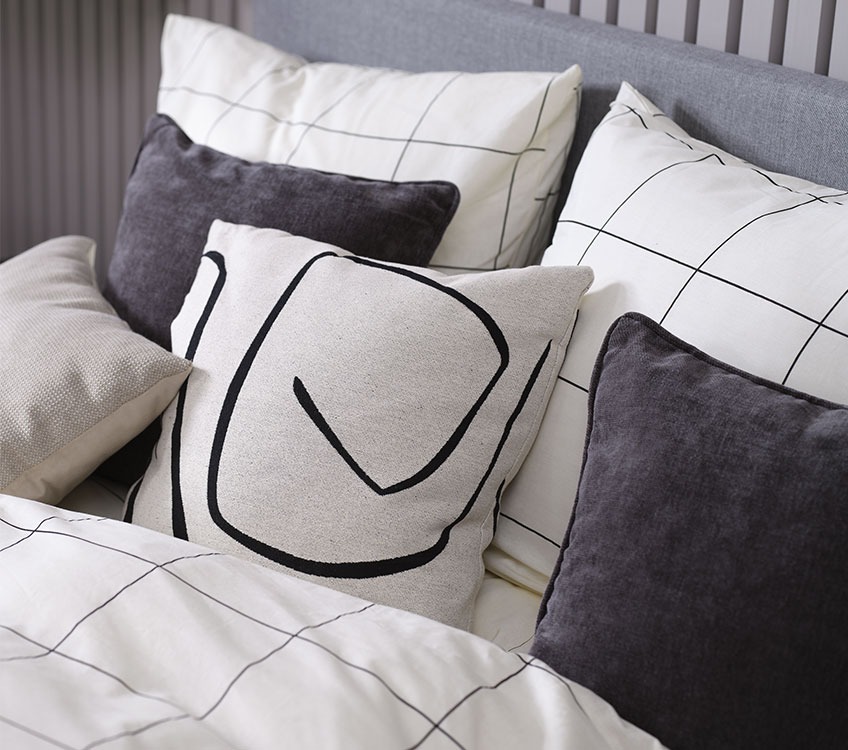 Lenzuola CRISTA, cuscino beige LILJE, cuscino decorativo HORNFIOL Camera da letto con biancheria da letto bianca e nera con cuscini decorativi