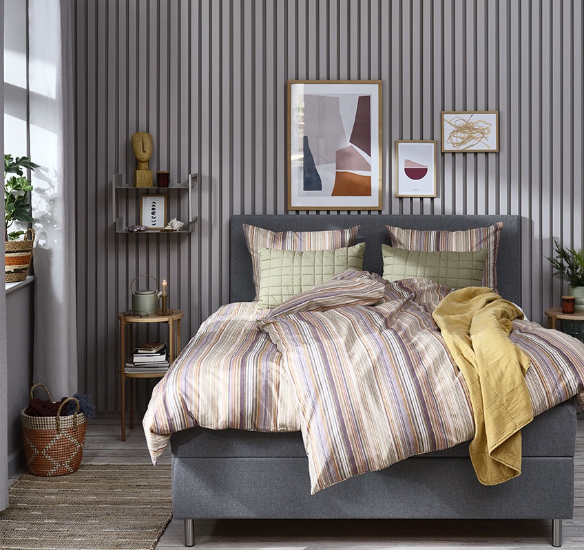Biancheria da letto ABBIE, coperta trapuntata gialla VALMUE e cuscino verde VALMUE Una camera da letto in stile con biancheria da letto a righe, letto giallo e cuscini verdi