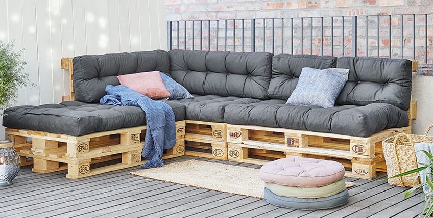 Grande divano angolare in pallet con estremità aperta in un patio
