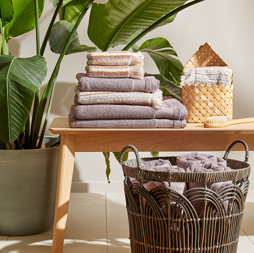Asciugamani di cotone e un cesto di vimini su una panca in un bagno