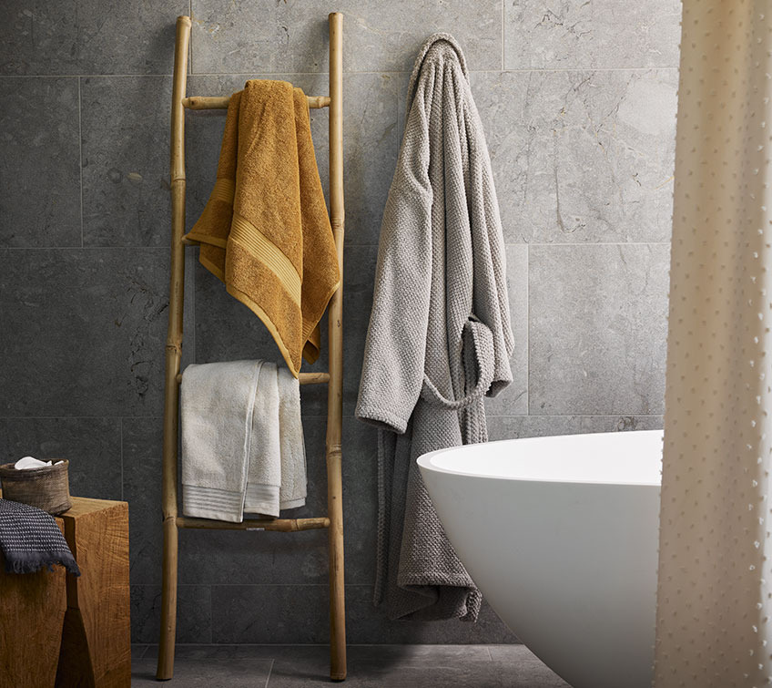 Asciugamani KARLSTAD e SORUNDA, accappatoio BULLMARK Scala decorativa con asciugamano giallo e bianco e accappatoio grigio chiaro in bagno