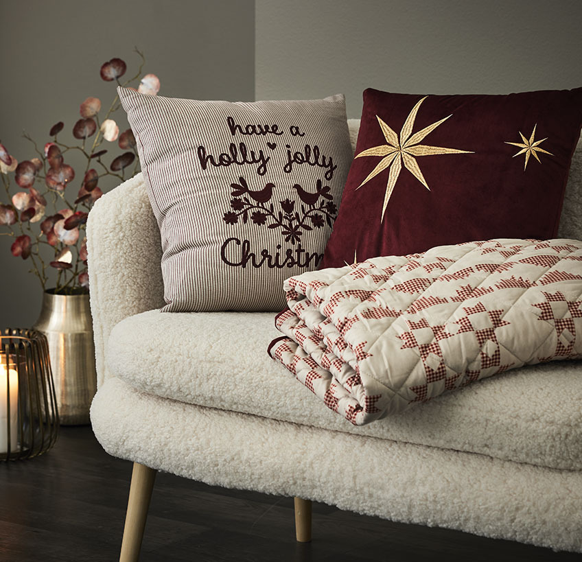 Cuscini e coperta trapuntata con motivi natalizi su un divano bianco