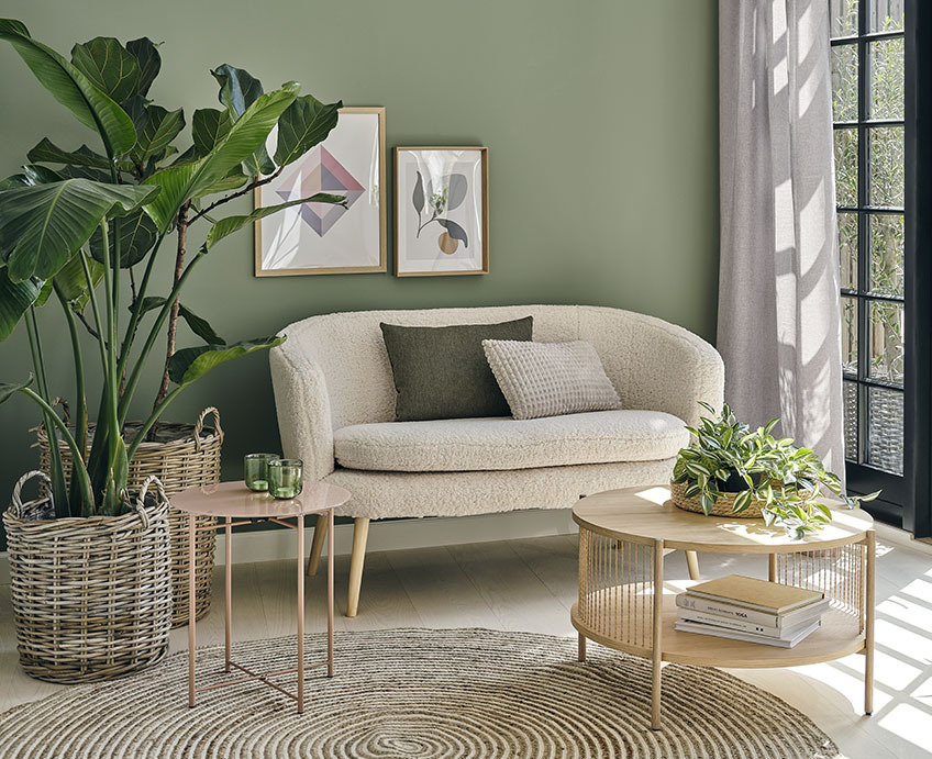 Soggiorno con divano bianco, tavolino in rovere e piante verdi