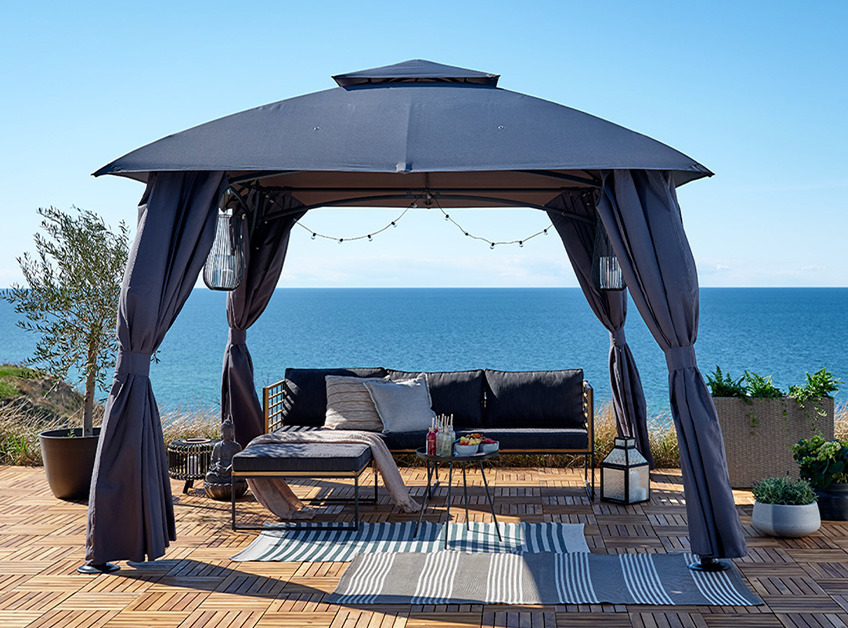 Gazebo grigio con set da salotto e decorazioni con vista sul mare